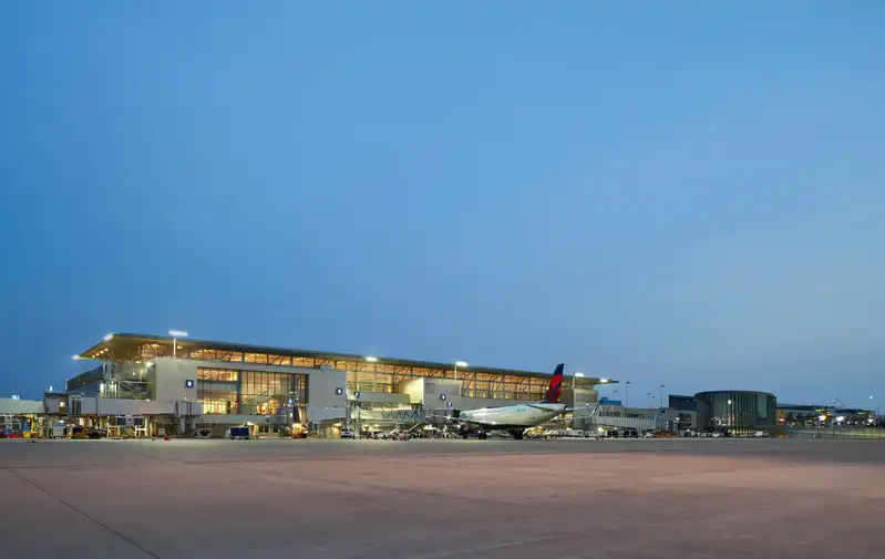Twilight view of Austin-Bergstrom International Airport with the terminal buildings illuminated and commercial airplanes at the gates, captured from the tarmac level.
